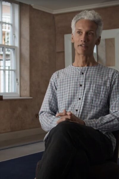 Kevin Le Gendre sits on a green chair, with a book open on his lap