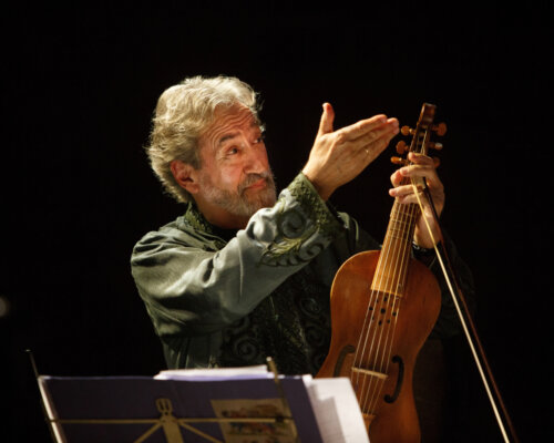 Catalan man holding viol and raising his hand and smiling music stand