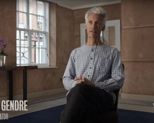 Kevin Le Gendre sits on a green chair, with a book open on his lap